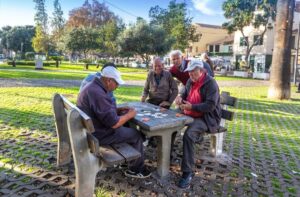 Four older men gather around a park table playing cards