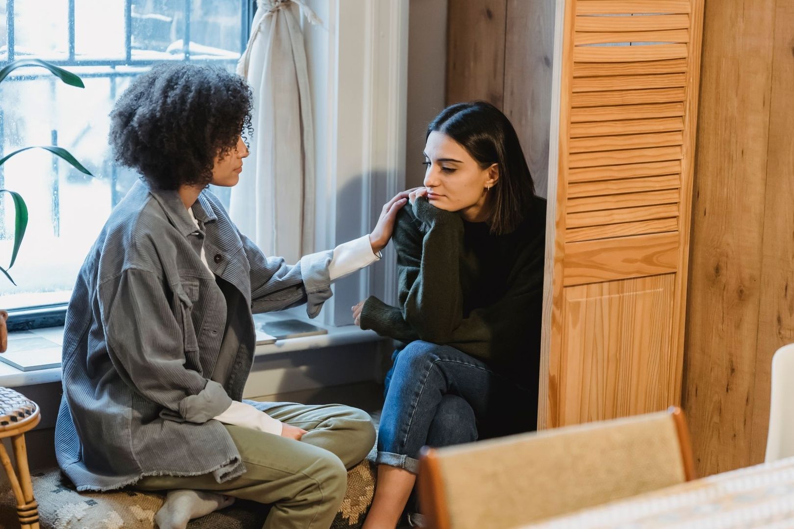 Two women having a quiet, supportive conversation at home